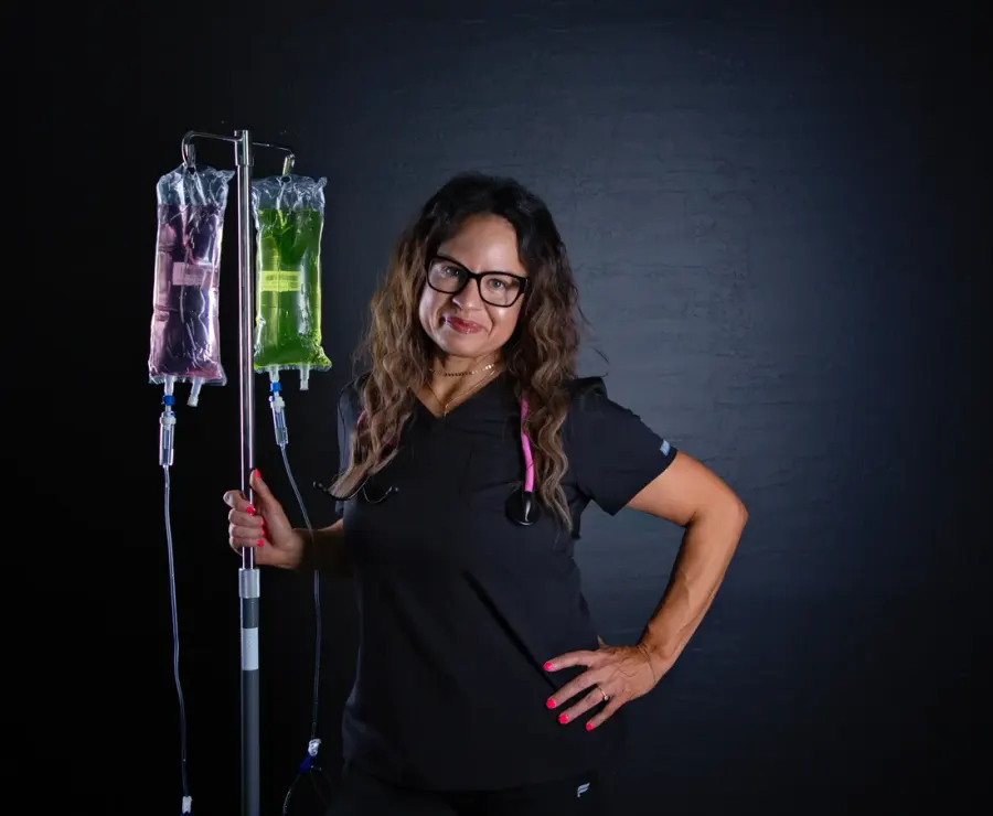 Angela in scrubs beside an IV stand